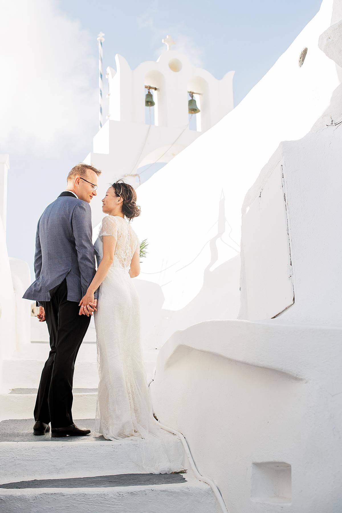 bride and groom portrait session with a washed out white church in Santorini
