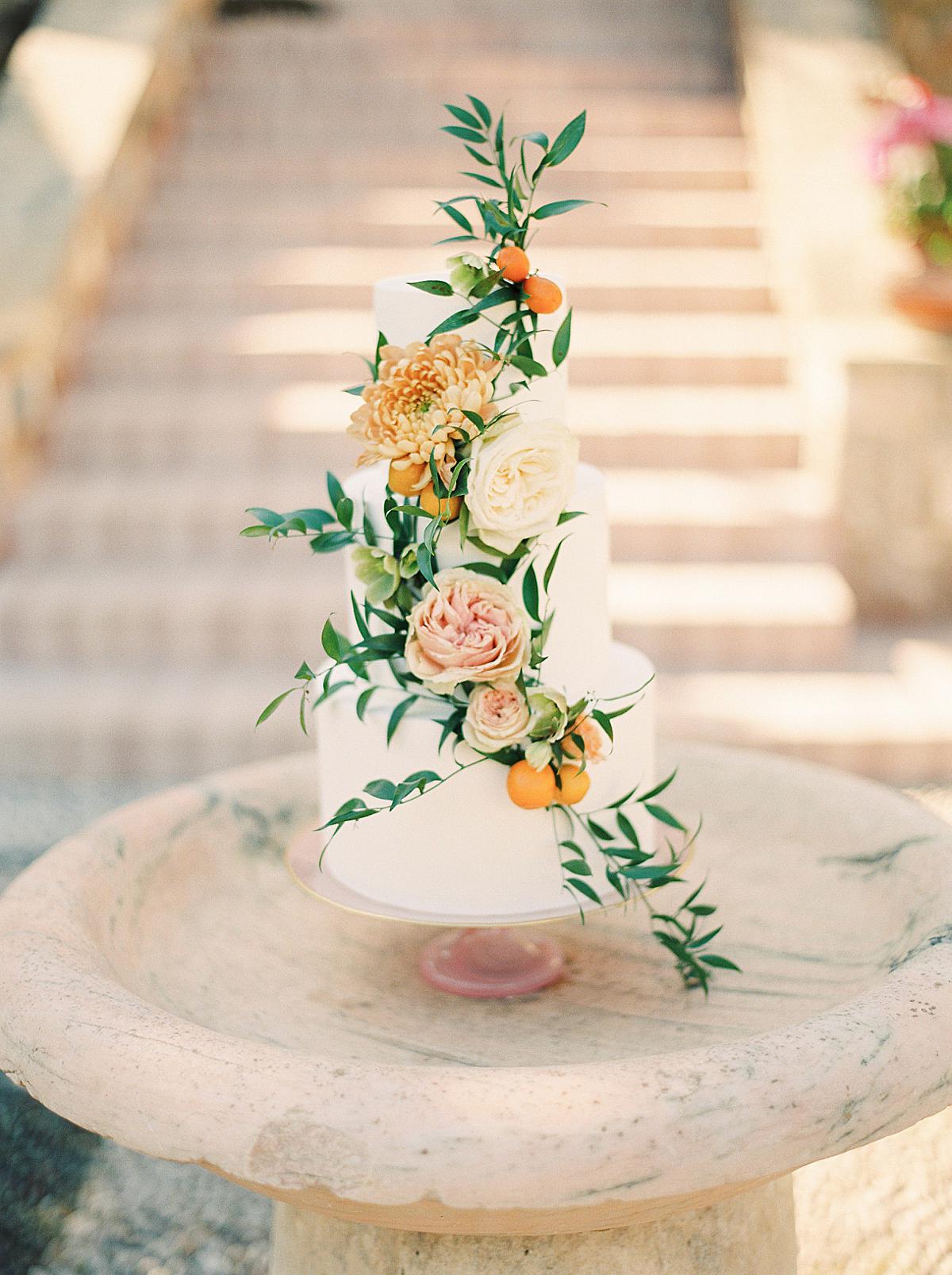 three tier white colored destination wedding cake with some natural florals
