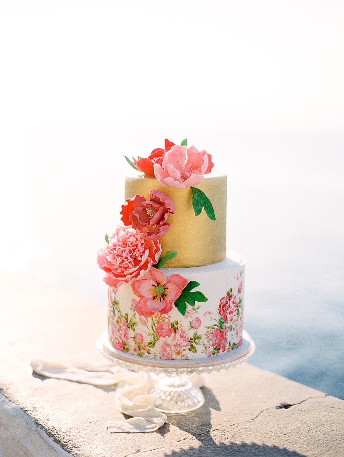 two tiers destination wedding cake that is very colorful and with flower details painted by hand for a hydra wedding