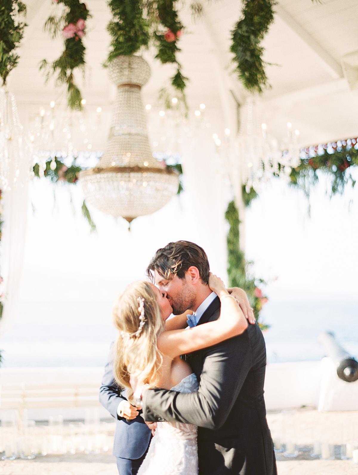 groom kissing bride at sunset restaurant on Hydra island