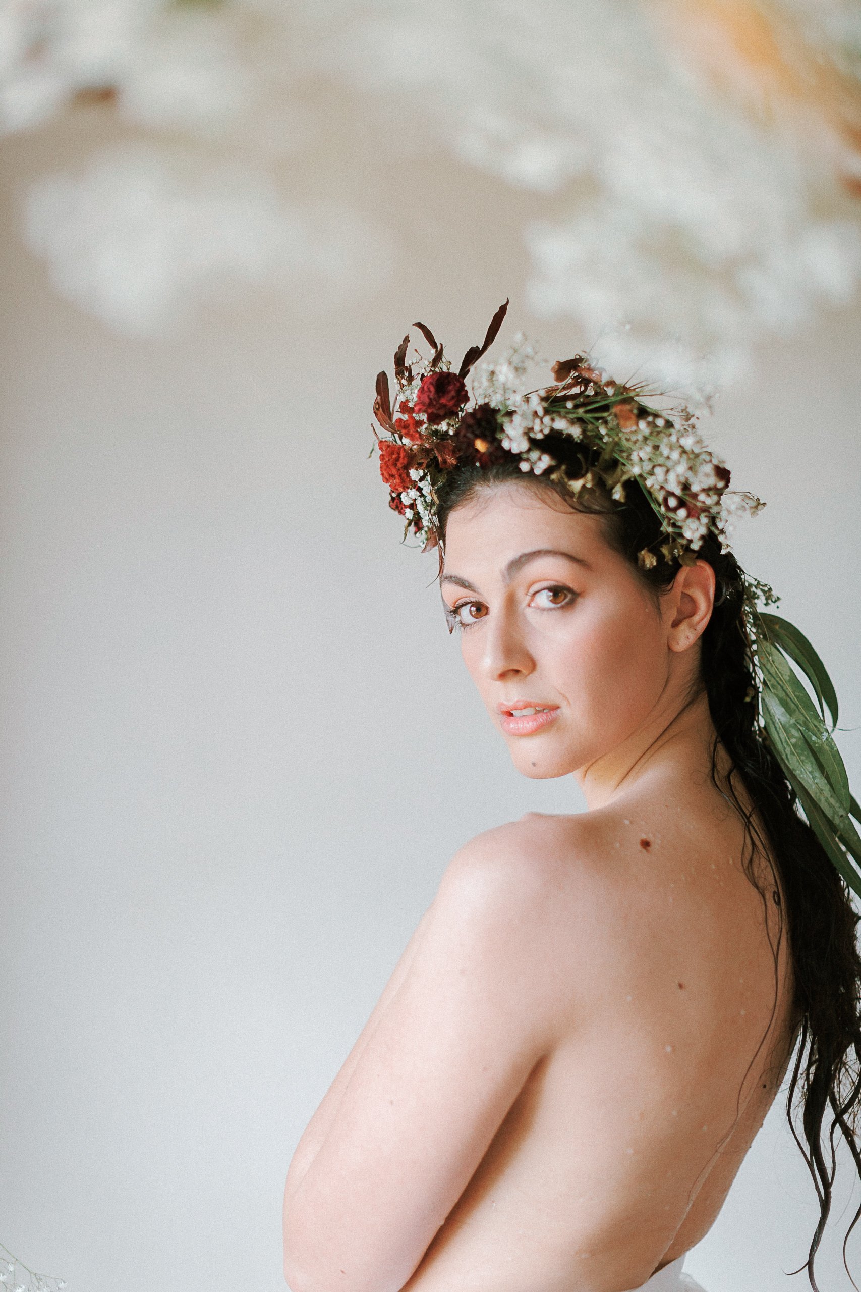 woman wiht black hair wearing a flower crown for a fine art bridal boudoir session