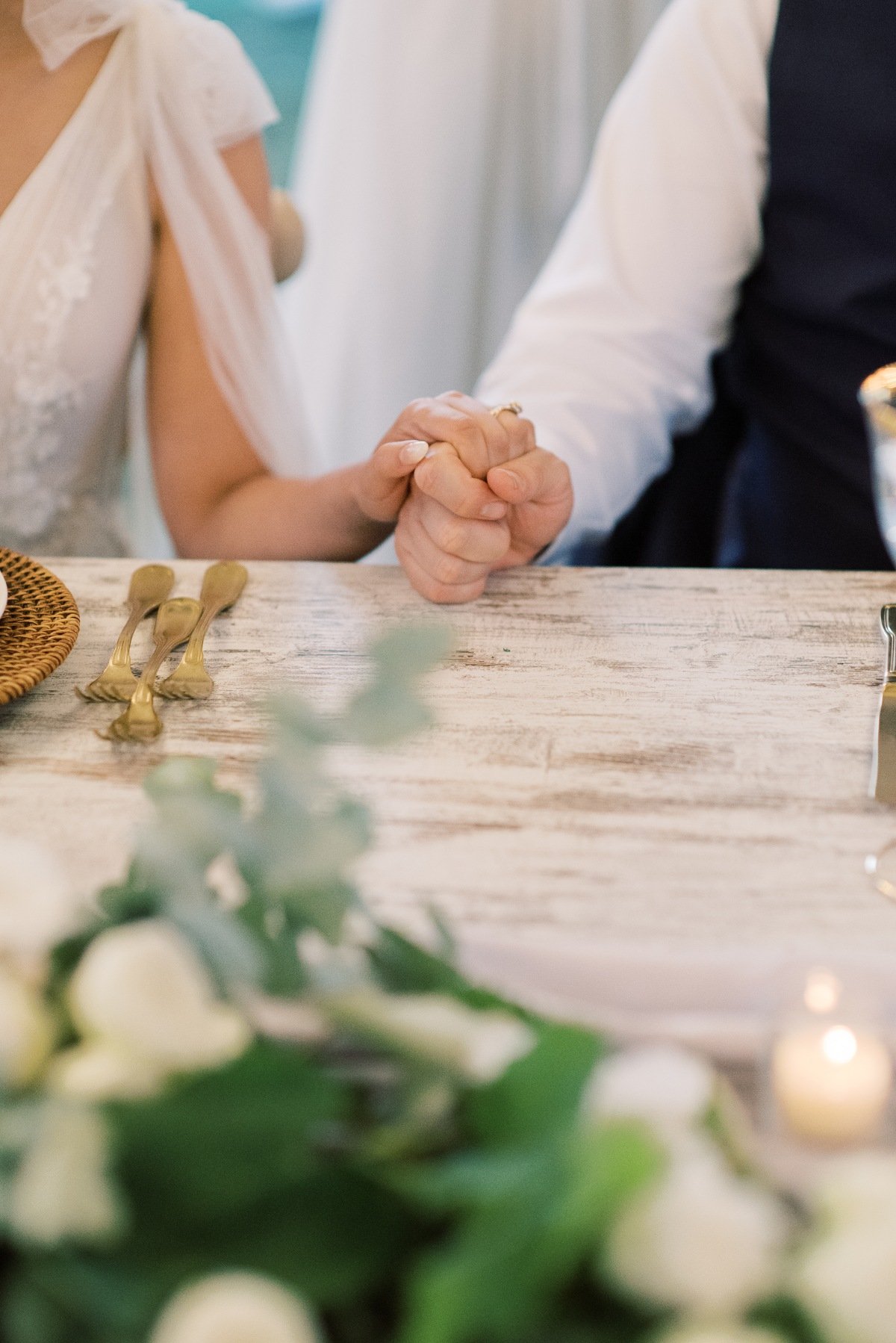 bride and groom holding hands at the wedding table 