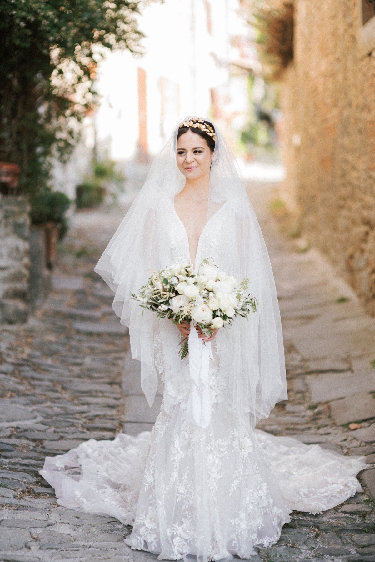 bride in white dress and gold head piece holding her bridal bouquet photographed by les anagnou