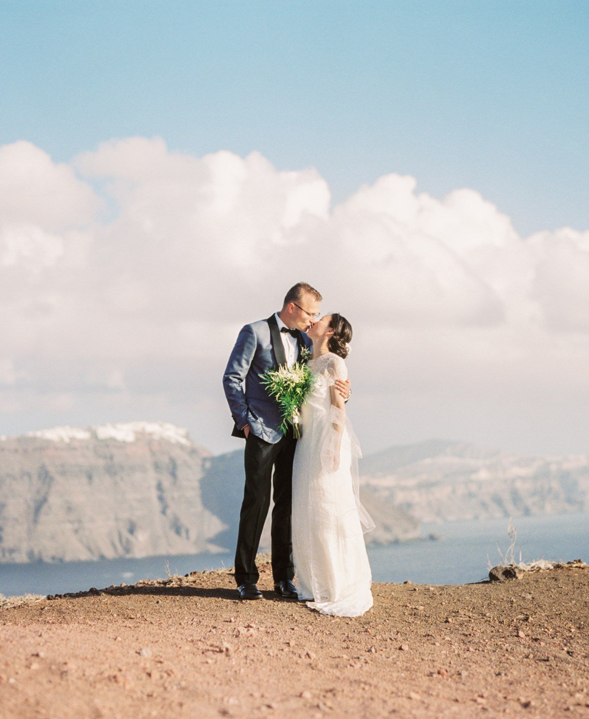 why hire local vendors - wedding photographer greece - bride and groom kissing overlooking the Caldera